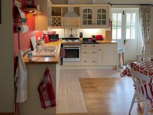a kitchen with white cabinets and a wooden floor at Le Jardin in Rodmarton