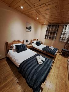 two beds in a room with wooden floors and wooden ceilings at Chalet de montagne style savoyard, vue sur pistes in Châtel