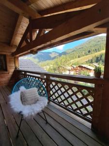 a chair sitting on a wooden deck with a view at Chalet de montagne style savoyard, vue sur pistes in Châtel