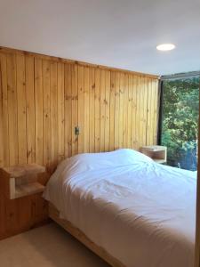 a bedroom with a bed and a wooden wall at RAMAL LODGE CONSTITUCION in Constitución