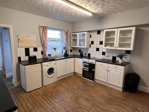 eine Küche mit weißen Schränken, einer Waschmaschine und einem Trockner in der Unterkunft ST Nic House in Carlisle