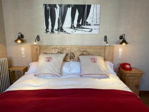 a bed with two pillows and a picture on the wall at Hôtel du Lion d'Or in Cauterets