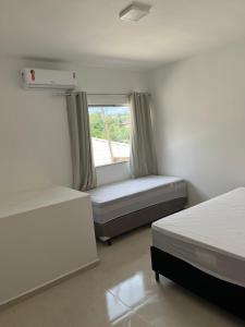 a bedroom with two beds and a window at Casa com piscina em Coroa Vermelha in Santa Cruz Cabrália
