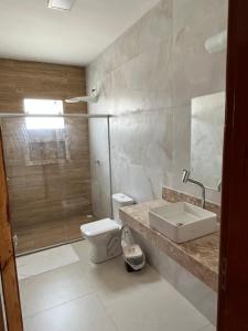 a bathroom with a toilet and a sink and a shower at Casa com piscina em Coroa Vermelha in Santa Cruz Cabrália