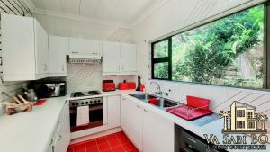 a kitchen with white cabinets and a large window at Va sabi bo, Best View, Luxury Family Villa in Hartbeespoort Dam in Hartbeespoort