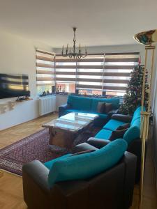 a living room with blue couches and a christmas tree at APARTMENTS VRANAS Bjelašnica in Bjelašnica