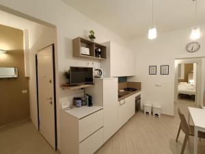 a kitchen with white cabinets and a living room at FirstHouse - nel centro storico con Parcheggio Gratuito in Siena