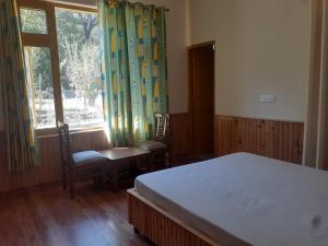 a bedroom with a bed and two chairs and a window at Gazing Moon Homestay in Shamshi