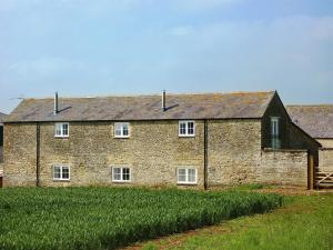 a brick building with a roof on a field at The Stalls - Nac in Aynho