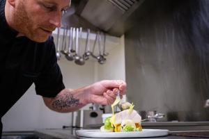 a man in a kitchen preparing a plate of food at Atlantic Hôtel & Spa in Les Sables-d'Olonne