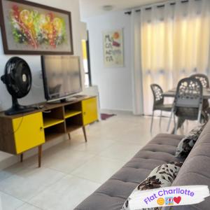 sala de estar con TV y sofá en Flat Charllotte, en Porto de Galinhas