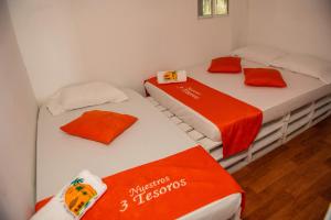 two beds in a room with orange and white sheets at Nuestros Tres Tesoros II in Playa Blanca