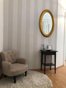 une chambre avec une chaise, un miroir et une table dans l'établissement Gründerzeitwohnung in beliebter Südvorstadt, à Leipzig