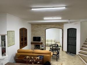 uma sala de estar com um sofá e uma televisão em Recanto Alpinista natureza e aventura para família e casais de amigos em Monte Verde