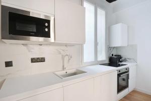 eine weiße Küche mit einer Spüle und einer Mikrowelle in der Unterkunft Lovely 2BR - Near La Sorbonne & Quartier Latin in Paris