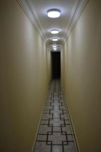 a long hallway with a tile floor and a black doorway at Seymur’s house in Quba