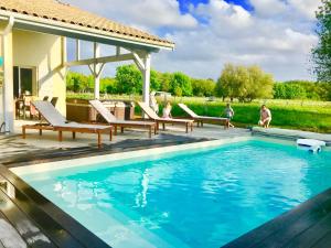 a swimming pool with chairs and a house at Villa Landaise piscine chauffée&jacuzzi Plage Clim Fibre in Sainte-Eulalie-en-Born