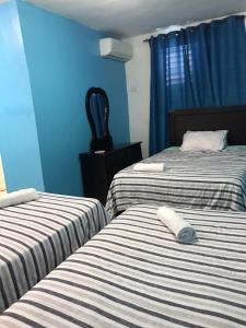 2 camas en una habitación con paredes azules en Hostal Magisterial Santo Domingo, en Santo Domingo