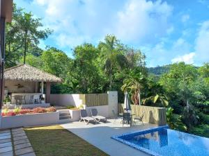 un patio trasero con piscina y una villa en RIVERSIDE RETREAT (SEYCHELLES), en Mahe