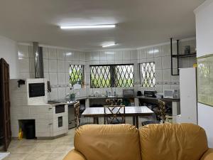 uma sala de estar com um sofá e uma cozinha em Recanto Alpinista natureza e aventura para família e casais de amigos em Monte Verde