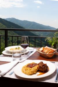 una tavola con un piatto di cibo e un bicchiere di vino di Ostello Scudellate by Stay Generous a Scudellate