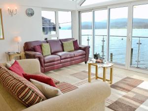 sala de estar con sofá y vistas al agua en Spout Crag Boathouse, en Far Sawrey