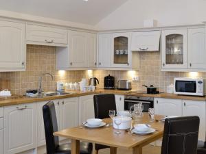 a kitchen with white cabinets and a wooden table at Spout Crag Boathouse in Far Sawrey