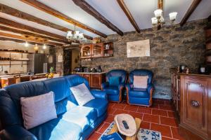 sala de estar con muebles de cuero azul y pared de piedra. en Stone House ''Vista'' By Atlantic Holiday, en São Vicente