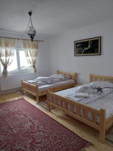 a bedroom with two beds and a rug at Casa din Deal-Apuseni in Ocoale