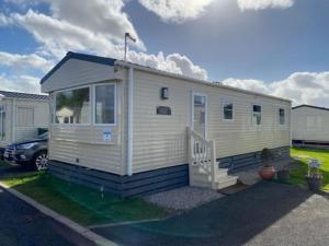 a small white tiny house with a porch at A family-friendly, eight birth, 2019 Abbey Trieste Caravan in Morecambe