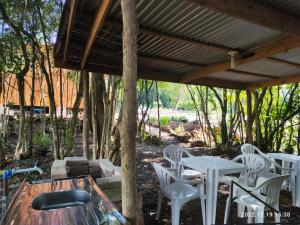 un patio con sillas blancas, mesa y árboles en Cabana, lagoas e natureza!, en Relvado