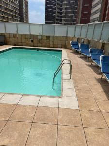 una piscina en la parte superior de un edificio con sillas azules en Oceanic Durban, en Durban