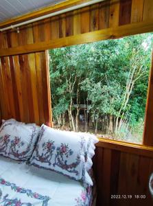 Cama con almohadas en habitación con ventana en Cabana, lagoas e natureza!, en Relvado