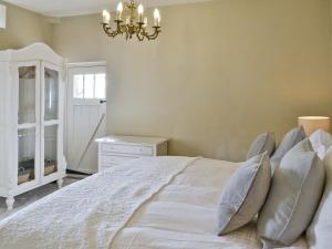 a bedroom with a bed with pillows and a chandelier at The Dovecote in Romaldkirk