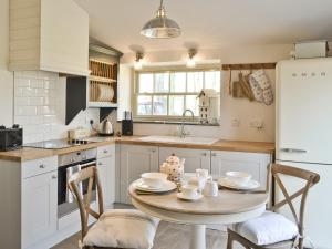 a kitchen with a table and chairs and a refrigerator at The Dovecote in Romaldkirk