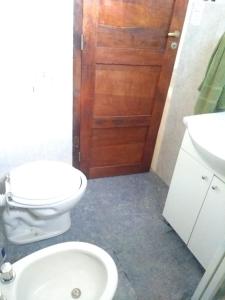 een badkamer met een toilet en een houten deur bij Casa en Amaicha in Amaichá del Valle