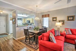 a living room with a red couch and a table at Myrtle Beach Condo in Tidewater with Pool and Golf! in North Myrtle Beach