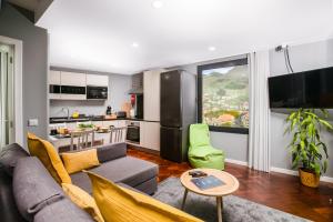 a living room with a couch and a kitchen at Rose House By Atlantic Holiday in Machico
