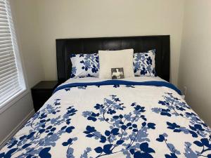 a bed with a blue and white comforter and pillows at Executive Apartment at Southend Sudbury in Sudbury