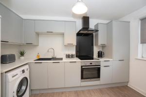 a kitchen with white cabinets and a washer and dryer at Pavlova House - Luxury 2 Bed Apartment in Aberdeen City Centre in Aberdeen