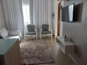 uma sala de estar com duas cadeiras e uma televisão em Apartamento Em Condominio Residencial Familiar em Cabo Frio
