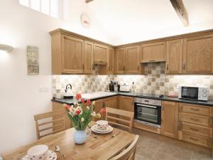 una cocina con armarios de madera y una mesa de madera con flores en Salem View - E5461 en Wainfleet All Saints