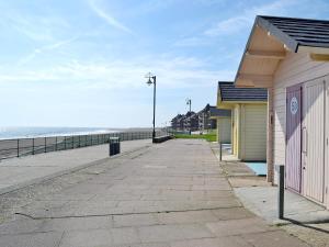 an empty sidewalk next to a beach with a building at Salem View - E5461 in Wainfleet All Saints