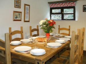 een houten tafel met witte borden en bloemen erop bij Cider House in Hawkchurch