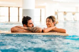 un hombre y una mujer tumbados en una tabla de surf en una piscina en Aqua Montis Resort & Spa en Rivisondoli