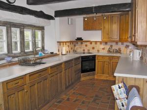 a kitchen with wooden cabinets and a stove top oven at Angram Farmhouse in Deepdale