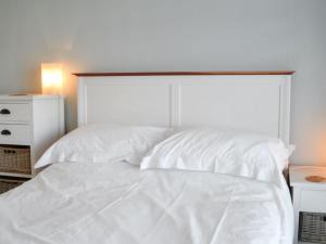 a white bed with a large headboard and a night stand at Bosuns Locker in Lymington