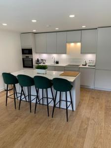 uma cozinha com cadeiras verdes e um balcão branco em Lux 2 Bedroom Ground Floor Apartment em Edinburgo