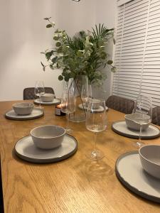 una mesa con platos y vasos y un jarrón con flores en Lux 2 Bedroom Ground Floor Apartment, en Edimburgo