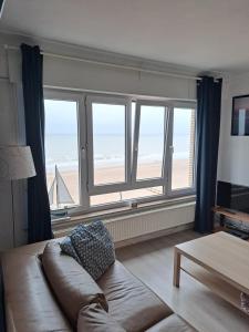 a living room with a couch and a large window at Appartement Zeedijk Blankenberge - near Brugge in Blankenberge